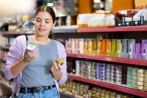 Difference Between Dog Food and Cat Food Young happy woman choosing canned pet food in pet
